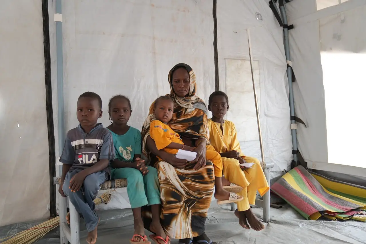 "A displaced Sudanese mother and her four children inside a shelter tent